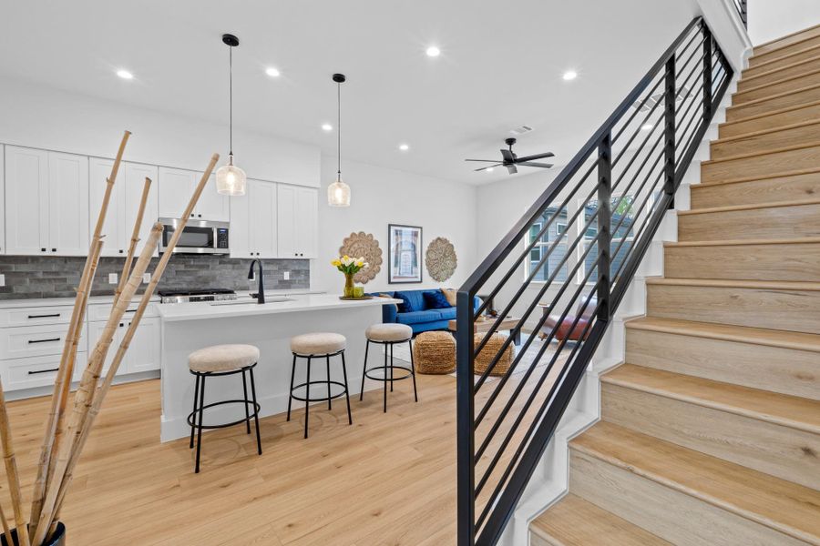 Kitchen with a kitchen island with sink, decorative light fixtures, ceiling fan, backsplash, and a breakfast bar area