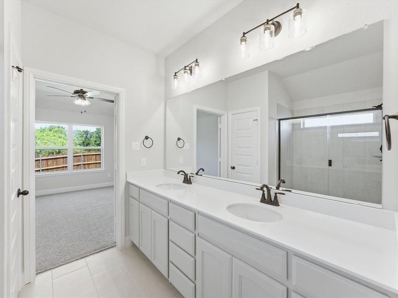 Dual vanity with white cabinetry, integrated sinks, white countertops, and bronze fixtures Dual vanity with white cabinetry, integrated sinks, white countertops, and bronze fixtures
