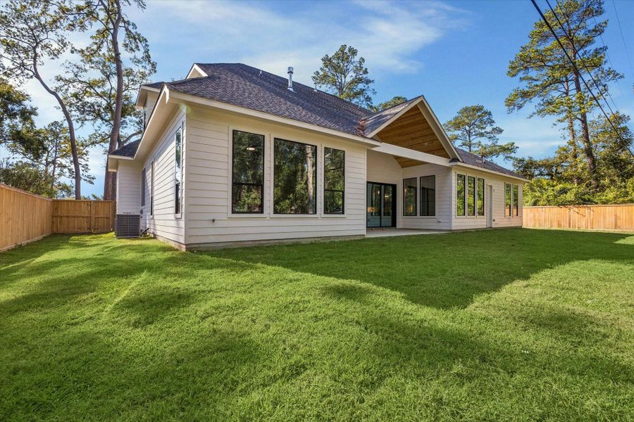 Spacious backyard with covered patio, expansive lawn, and large rear windows overlooking the outdoor space.