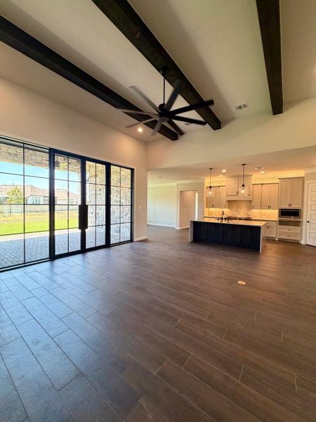 Dark ceiling beams and wood-look tile floors define this airy, open-concept living space.