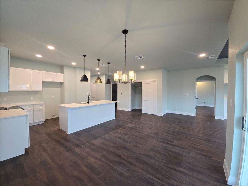 Kitchen featuring arched walkways, hanging light fixtures, a kitchen island with sink, recessed lighting, and a chandelier