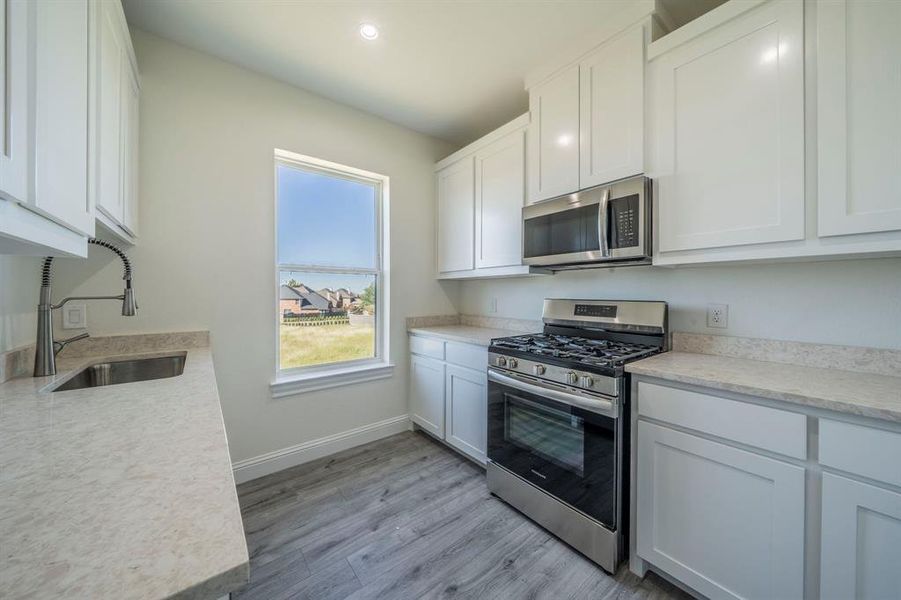 Kitchen featuring appliances with stainless steel finishes, white cabinets, and light wood finished floors Kitchen featuring appliances with stainless steel finishes, white cabinets, and light wood finished floors
