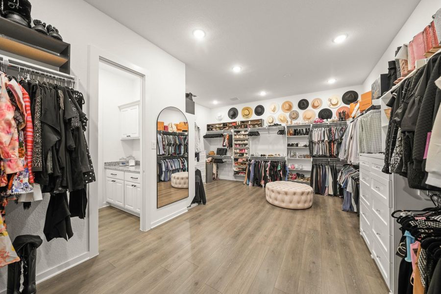 SPECTACULAR owner’s dream closet is custom built and measures 22’ x 15’ with Revwood waterproof floors, two built-in dressers with shelving above, separate shoe storage areas and double hanging rods and shelves. The laundry room sits to the left.