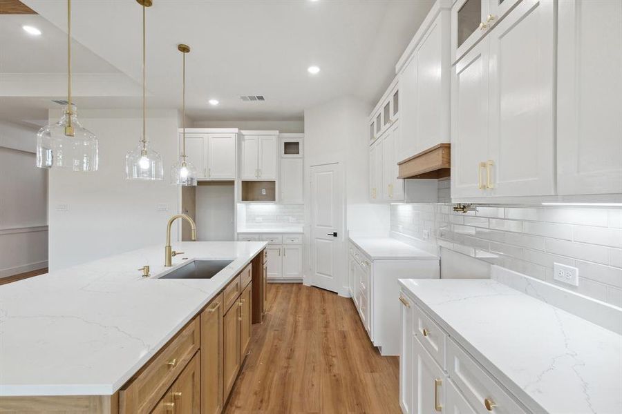 Kitchen with recessed lighting, light stone countertops, light wood-style floors, and a sink