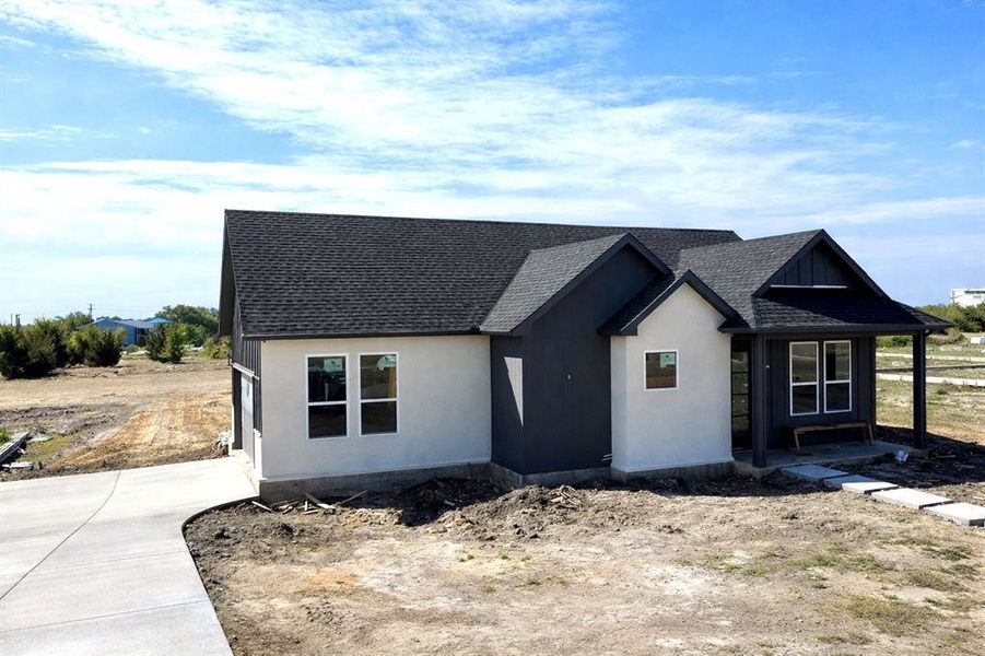 View of front facade with roof with shingles and stucco siding