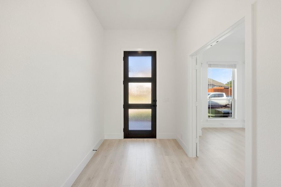 Entryway with dark front door featuring frosted glass panels and light hardwood floors Entryway with dark front door featuring frosted glass panels and light hardwood floors