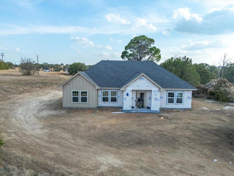 Property under construction with a shingled roof and board and batten siding
