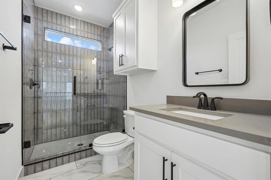 Bathroom featuring vanity, walk in shower, and toilet