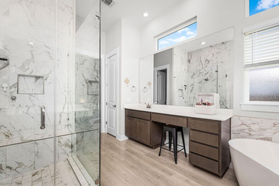 A well-lit primary bathroom features a spacious glass-enclosed shower, dual vanity, and a freestanding tub for luxurious comfort.