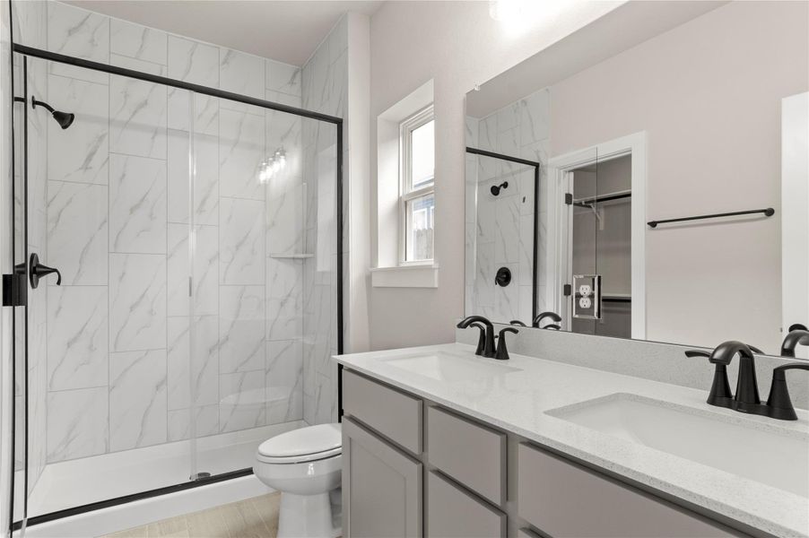 Full bathroom with toilet, a marble finish shower, double vanity, and a spacious closet Full bathroom with toilet, a marble finish shower, double vanity, and a spacious closet