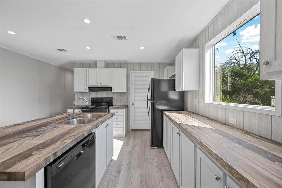 Kitchen with visible vents, black appliances, wood counters, and a sink