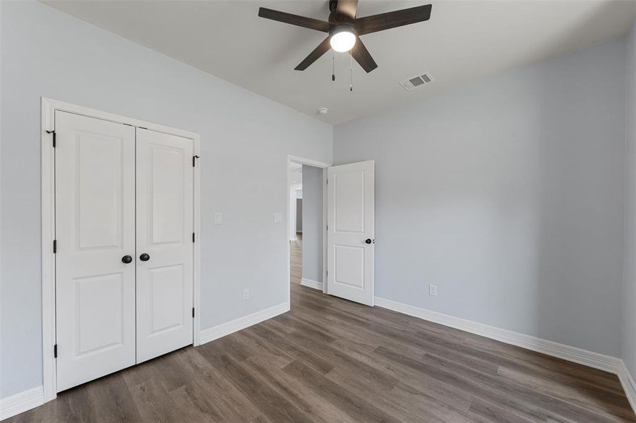 Unfurnished bedroom with dark wood finished floors, a ceiling fan, and a closet