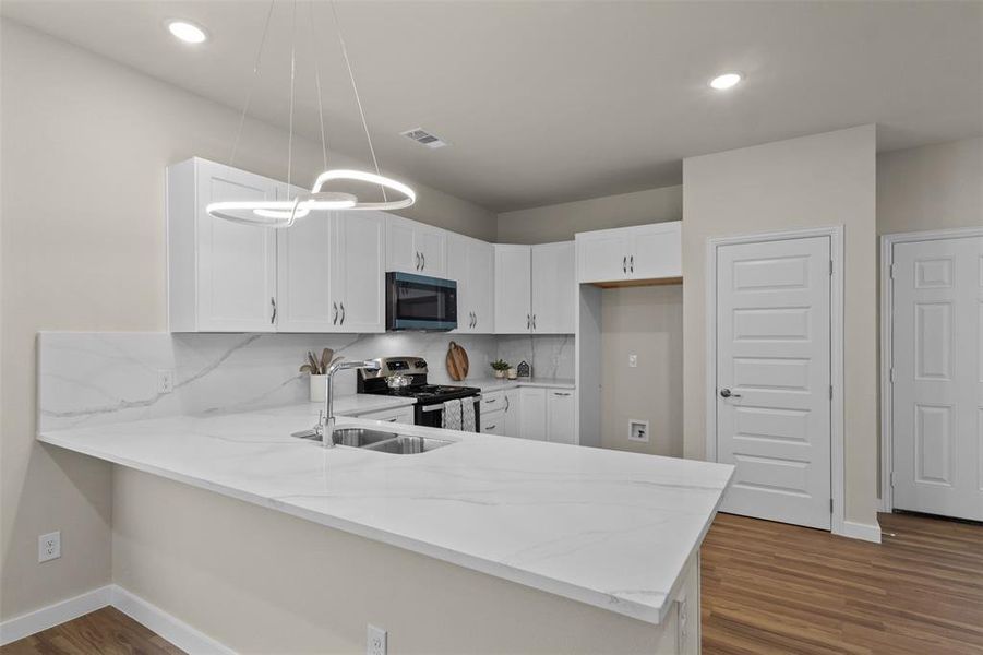 Kitchen featuring backsplash, white cabinetry, light stone counters, a peninsula, and recessed lighting Kitchen featuring backsplash, white cabinetry, light stone counters, a peninsula, and recessed lighting