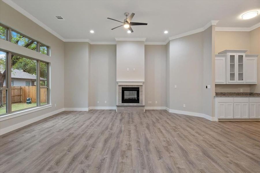 Unfurnished living room with ornamental molding, ceiling fan, and light hardwood / wood-style floors