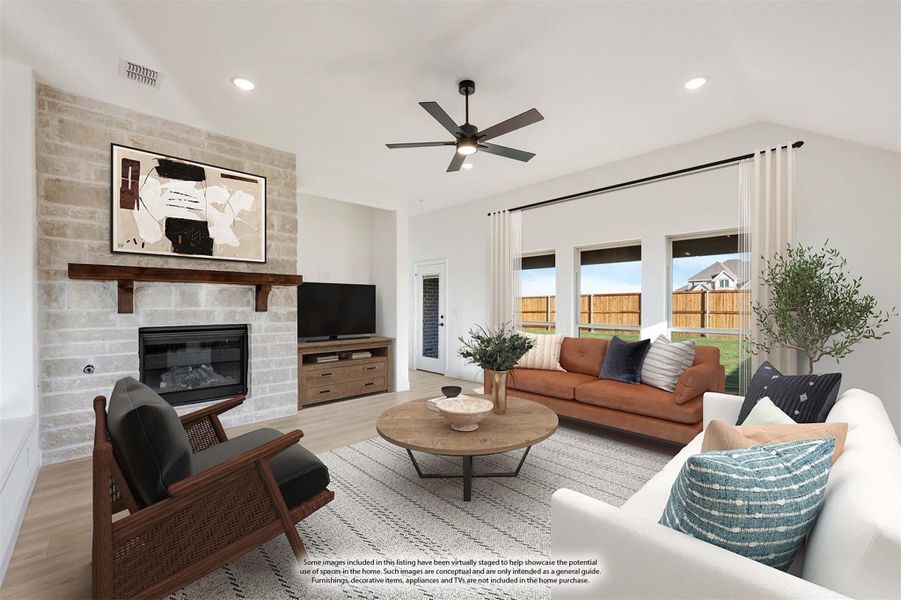 Living room with stone fireplace, ceiling fan, and large windows overlooking backyard Living room with stone fireplace, ceiling fan, and large windows overlooking backyard
