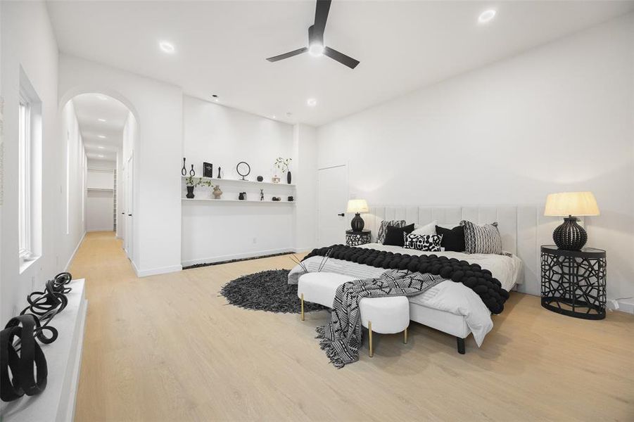Bedroom with light wood-style flooring, a walk in closet, arched walkways, recessed lighting, and a ceiling fan
