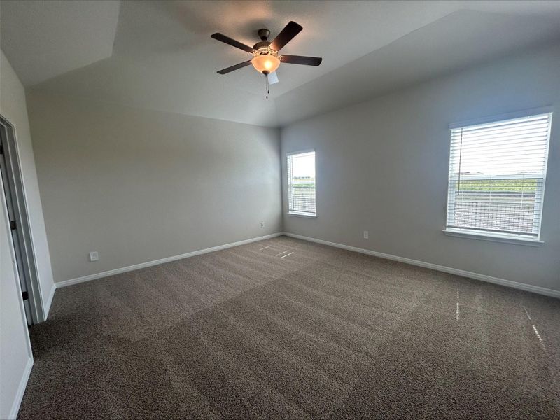 Empty room featuring ceiling fan, vaulted ceiling, and carpet floors Empty room featuring ceiling fan, vaulted ceiling, and carpet floors