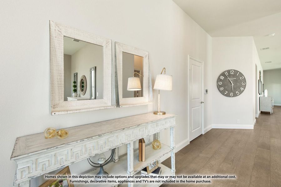 Hallway with console table, two framed mirrors, table lamp, and large wall clock on hardwood floors Hallway with console table, two framed mirrors, table lamp, and large wall clock on hardwood floors