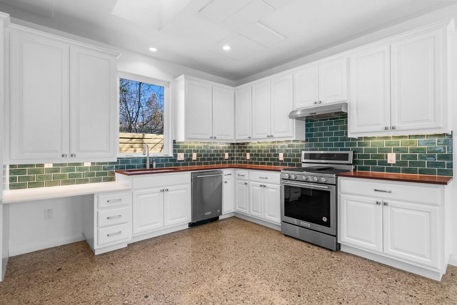 Fully equipped kitchen features sandstone countertops and stainless steel appliances, including a gas range.