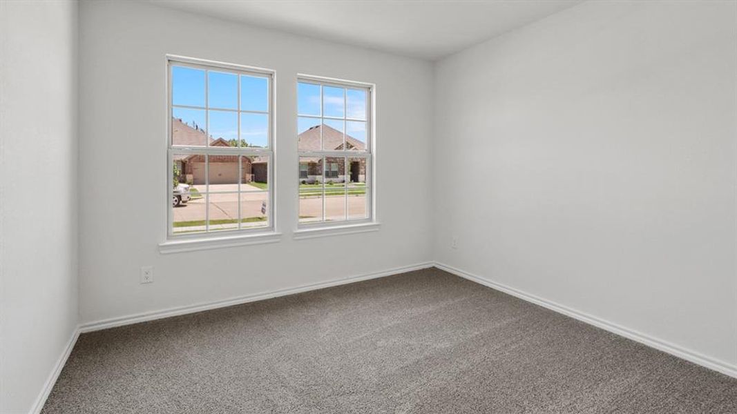 Room featuring dual windows with grids, neutral wall paint, and gray carpet flooring