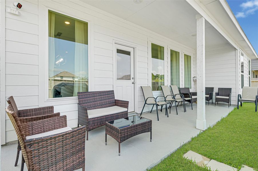 Charming covered patio with ample seating, perfect for outdoor relaxation and entertaining, overlooking a lush green lawn. Charming covered patio with ample seating, perfect for outdoor relaxation and entertaining, overlooking a lush green lawn.