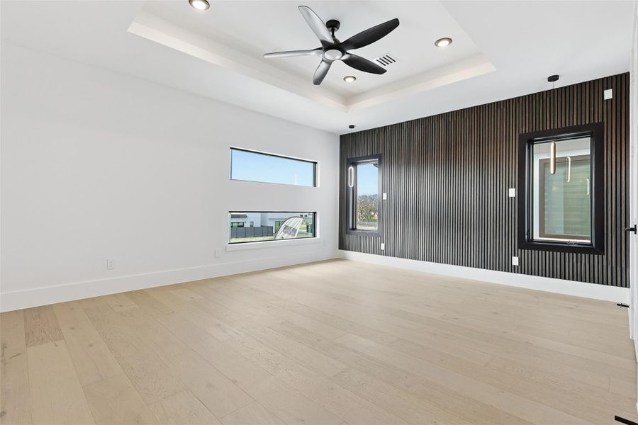 The Primary Bedroom features a dark wood slat accent wall and a tray ceiling with a contemporary fan.