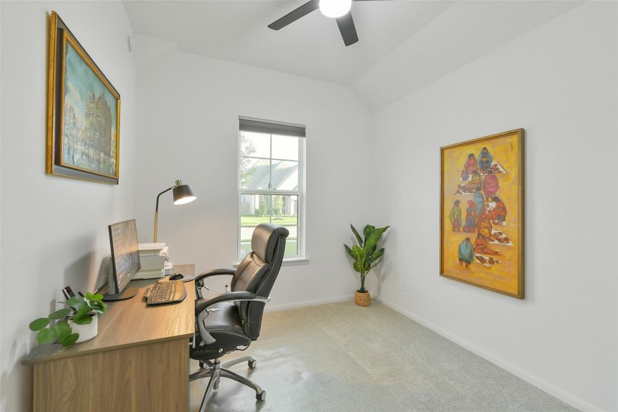 This secondary bedroom, currently used as a home office, features neutral paint, cozy carpet, and a ceiling fan.