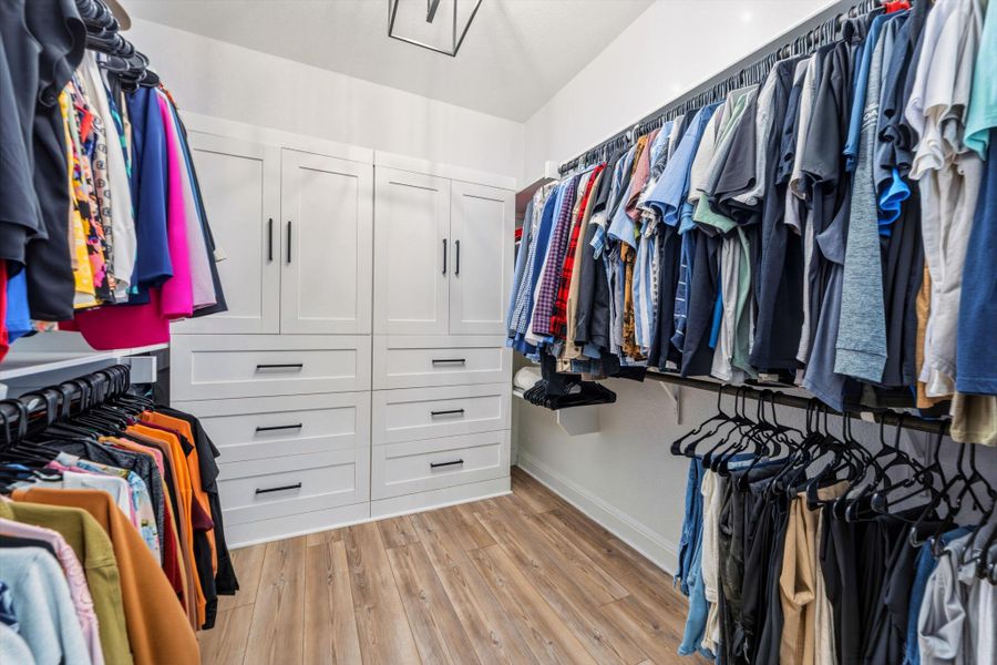 Custom closet system featuring white cabinetry, integrated drawers, and extensive hanging rods