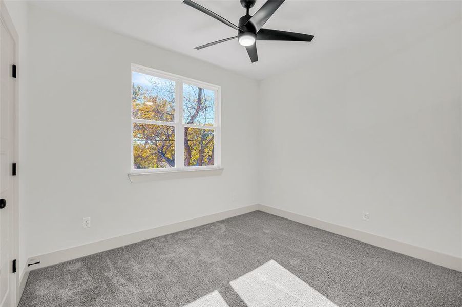 Carpeted empty room featuring baseboards and a ceiling fan