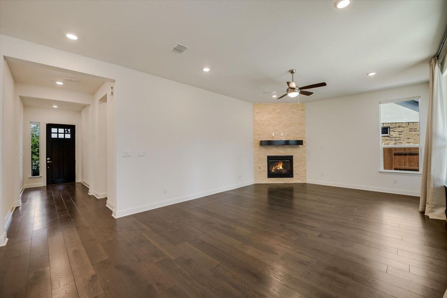 Unfurnished living room with dark wood-style floors, recessed lighting, ceiling fan, and a fireplace Unfurnished living room with dark wood-style floors, recessed lighting, ceiling fan, and a fireplace