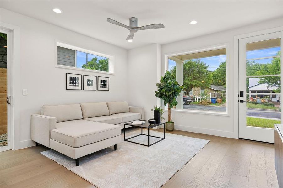 Living room full of light! Hardwood flooring, recessed lighting, ceiling fan.