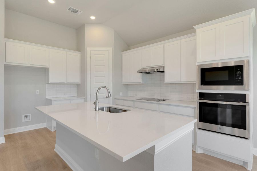 Kitchen with oven, built in microwave, under cabinet range hood, light wood-style floors, and white cabinets Kitchen with oven, built in microwave, under cabinet range hood, light wood-style floors, and white cabinets