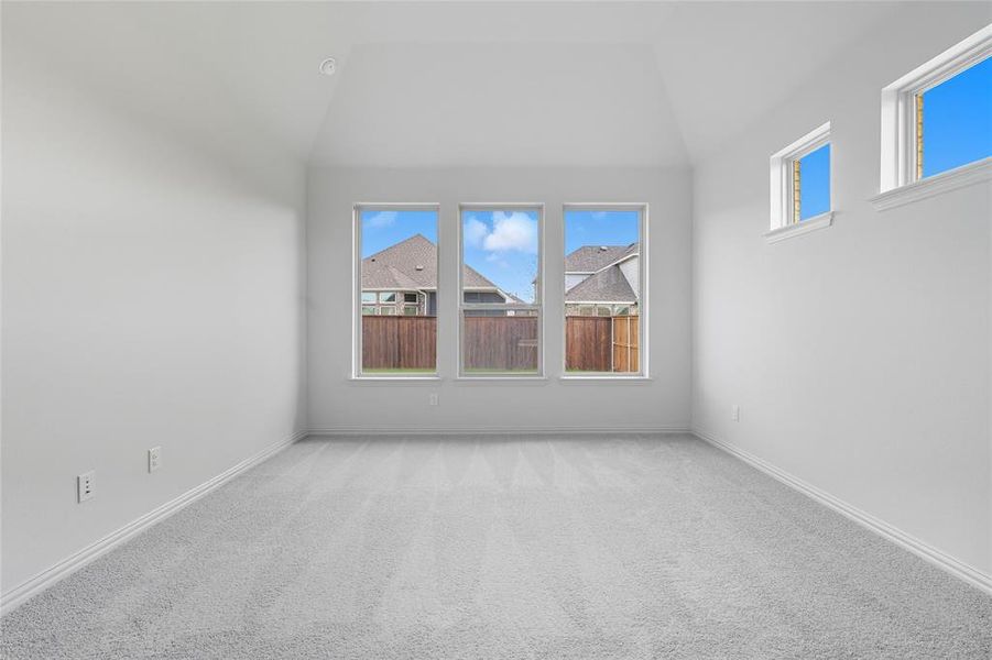 Carpeted empty room featuring baseboards and high vaulted ceiling Carpeted empty room featuring baseboards and high vaulted ceiling