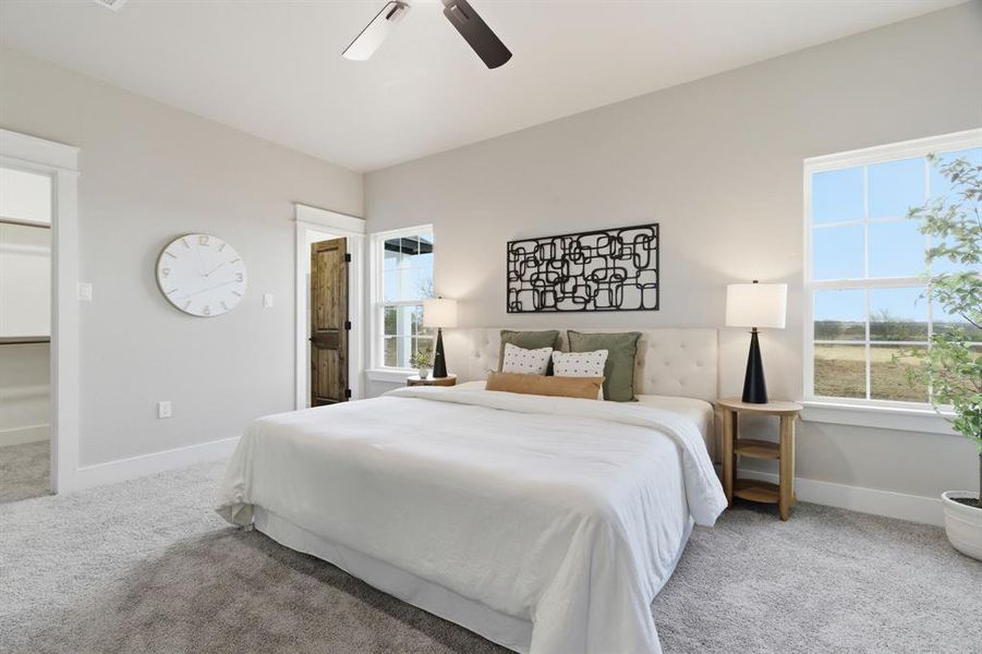 Bedroom with light carpet, a walk in closet, and a ceiling fan