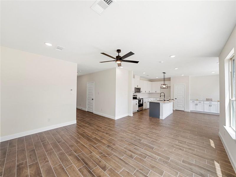 Unfurnished living room featuring sink, hardwood / wood-style floors, and ceiling fan