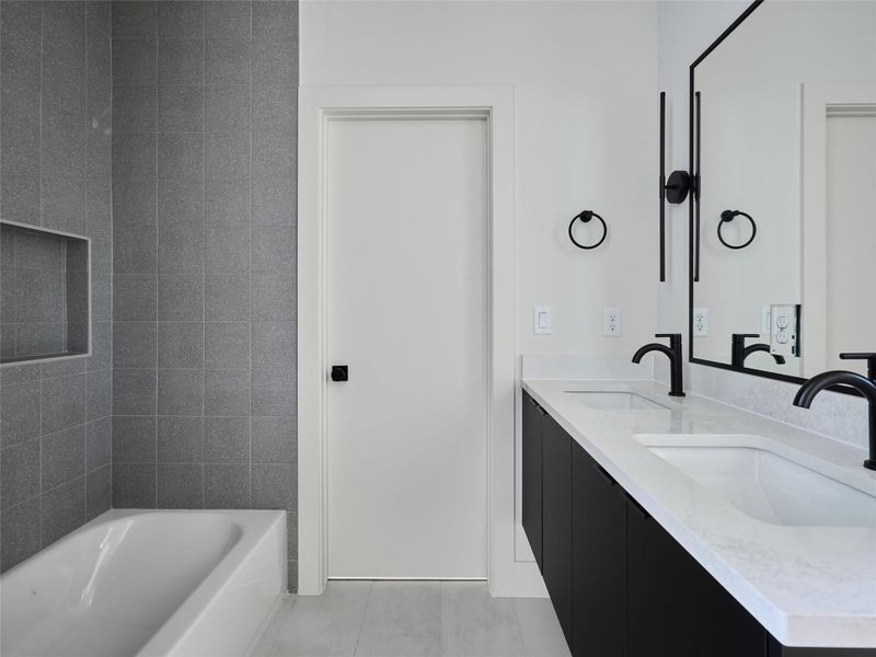 Bathroom with double vanity, a tub, and light tile patterned floors Bathroom with double vanity, a tub, and light tile patterned floors