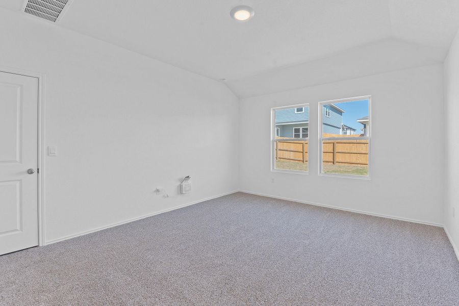 Carpeted spare room featuring vaulted ceiling, visible vents, and baseboards