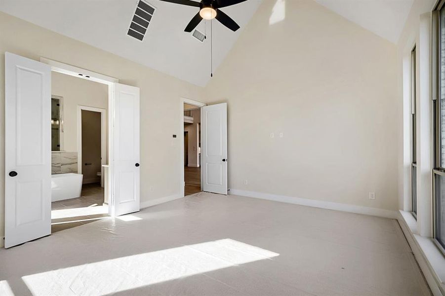 Unfurnished bedroom with vaulted ceiling, ceiling fan, and ensuite bathroom Unfurnished bedroom with vaulted ceiling, ceiling fan, and ensuite bathroom
