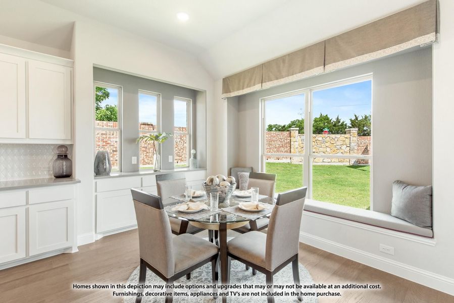 Bright dining area with round glass table, four gray chairs, window seat, and large windows overlooking backyard