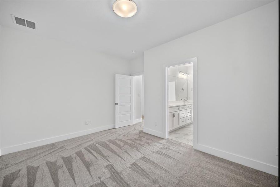 Unfurnished bedroom with light carpet and ensuite bathroom Unfurnished bedroom with light carpet and ensuite bathroom