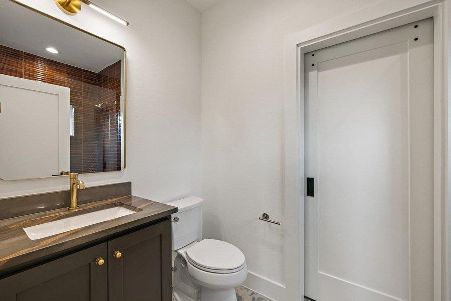 A well-appointed bathroom offers contemporary fixtures and a rich, tiled shower enclosure visible in the mirror's reflection.