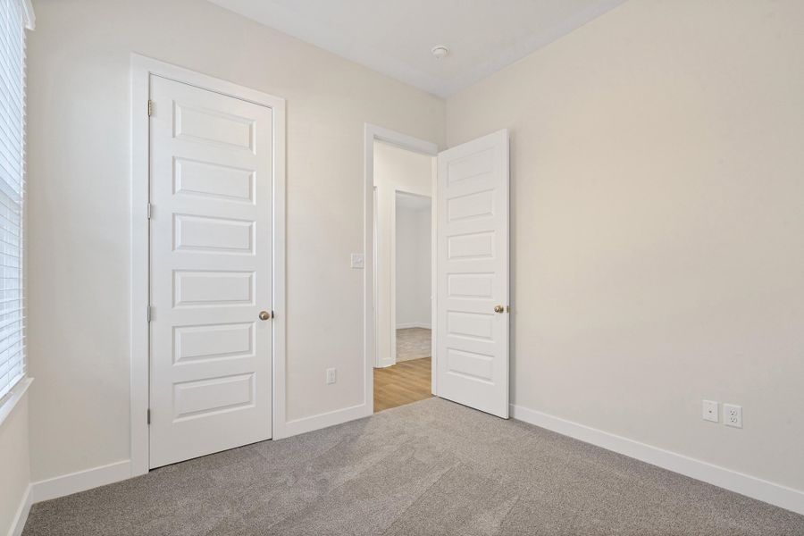 Unfurnished bedroom featuring light colored carpet and baseboards