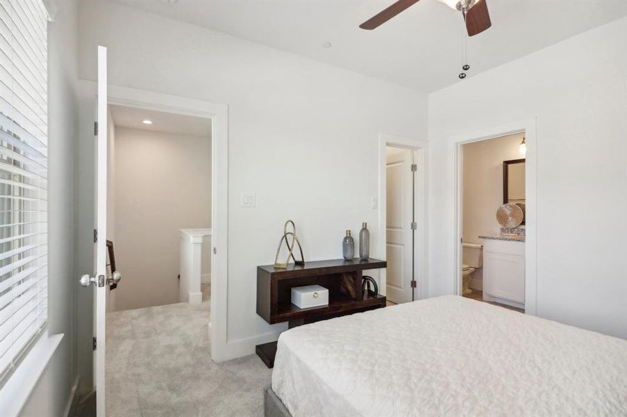 Bedroom featuring ensuite bath, ceiling fan, and light colored carpet