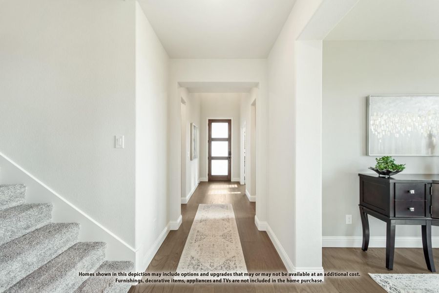 Bright entryway hallway with dark hardwood floors, runner rug, wood-framed front door, and carpeted staircase on the left. Bright entryway hallway with dark hardwood floors, runner rug, wood-framed front door, and carpeted staircase on the left.