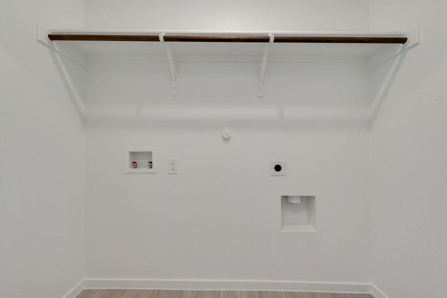 Washroom with hookup for a gas dryer, hookup for an electric dryer, hookup for a washing machine, and wood finished floors