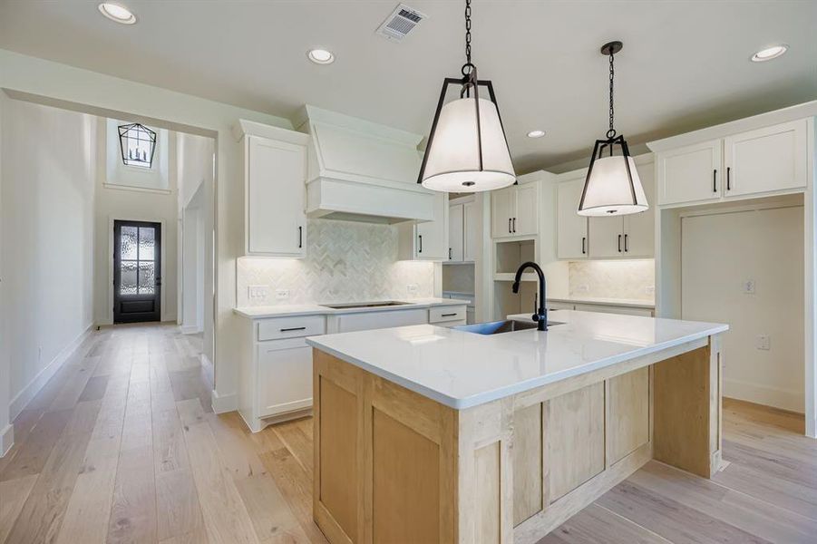 Kitchen featuring tasteful backsplash, light wood-style flooring, light stone counters, a kitchen island with sink, and recessed lighting Kitchen featuring tasteful backsplash, light wood-style flooring, light stone counters, a kitchen island with sink, and recessed lighting