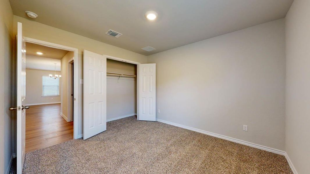 Unfurnished bedroom with carpet floors, a closet, and suspended lighting