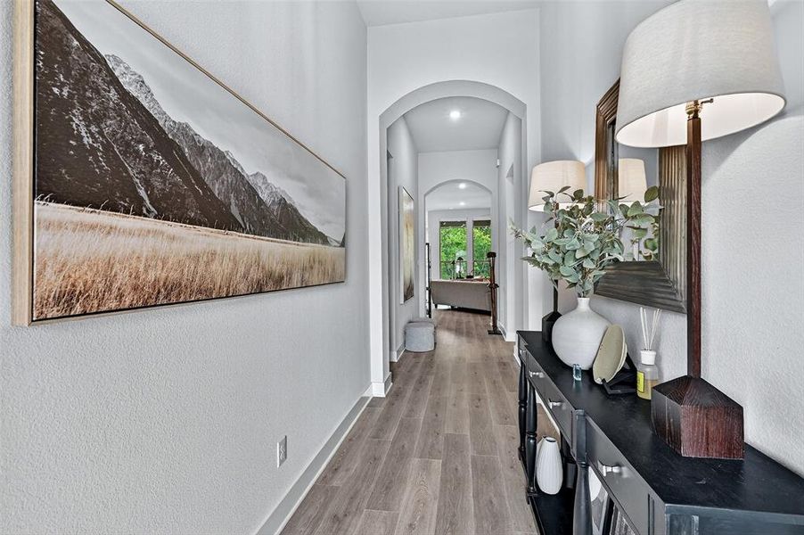 Hall featuring arched walkways and light wood-style floors Hall featuring arched walkways and light wood-style floors