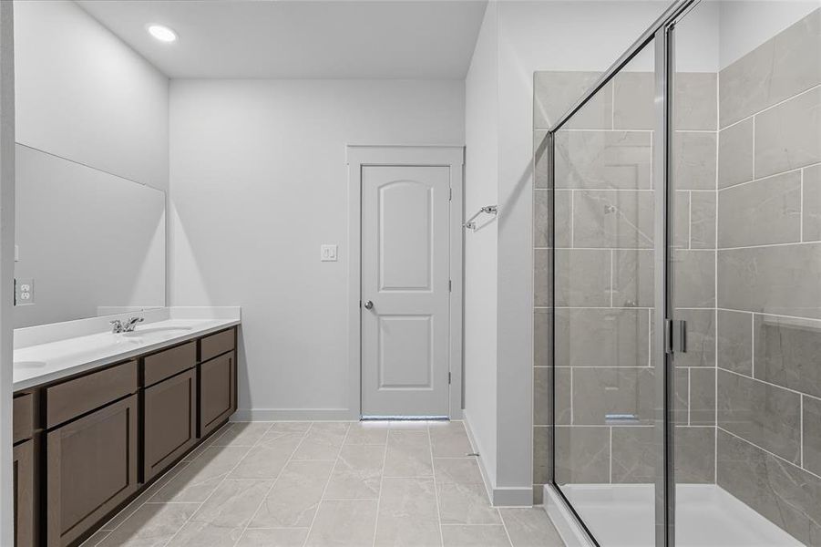 Full bathroom with a stall shower, double vanity, light tile patterned floors, and recessed lighting Full bathroom with a stall shower, double vanity, light tile patterned floors, and recessed lighting