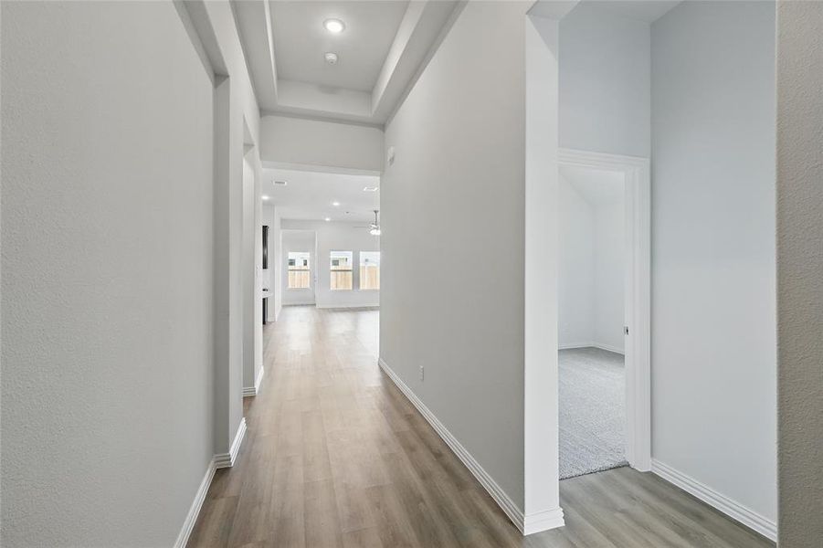 Hall featuring recessed lighting, light wood-type flooring, and a raised ceiling